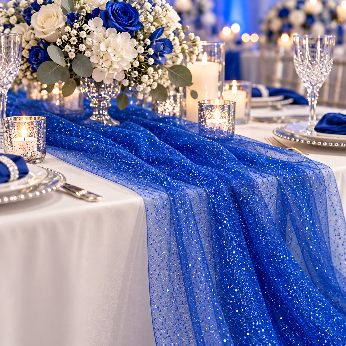 Esempio di allestimento tavola per cerimonia con tulle glitter blu Aura, fiori e candele