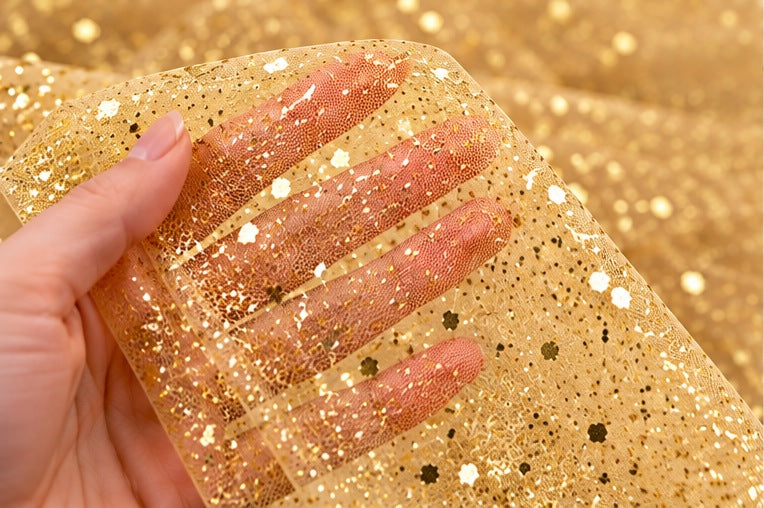 Tulle glitter oro Aura mostrato tra le mani per evidenziare la trama e la trasparenza