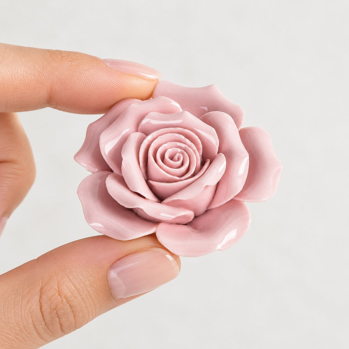 Rosa in ceramica rosa 5,8 cm tenuta tra le dita per mostrarne le dimensioni
