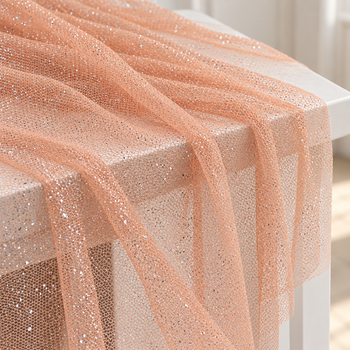 Tulle pesca Aura con glitter argentati drappeggiato su un tavolo bianco per decorazioni